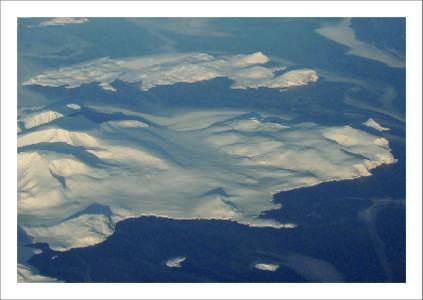 EditIoN hANs volKERt – 2o11 for IAMAS #1: „White mountains in dark sea“ Big Island behind Domes (750 m; 58.5o N, 62.75o W) seen from 9700 m North Labrador coast, Canada, January 2010  EditIoN hANs volKERt – 2o